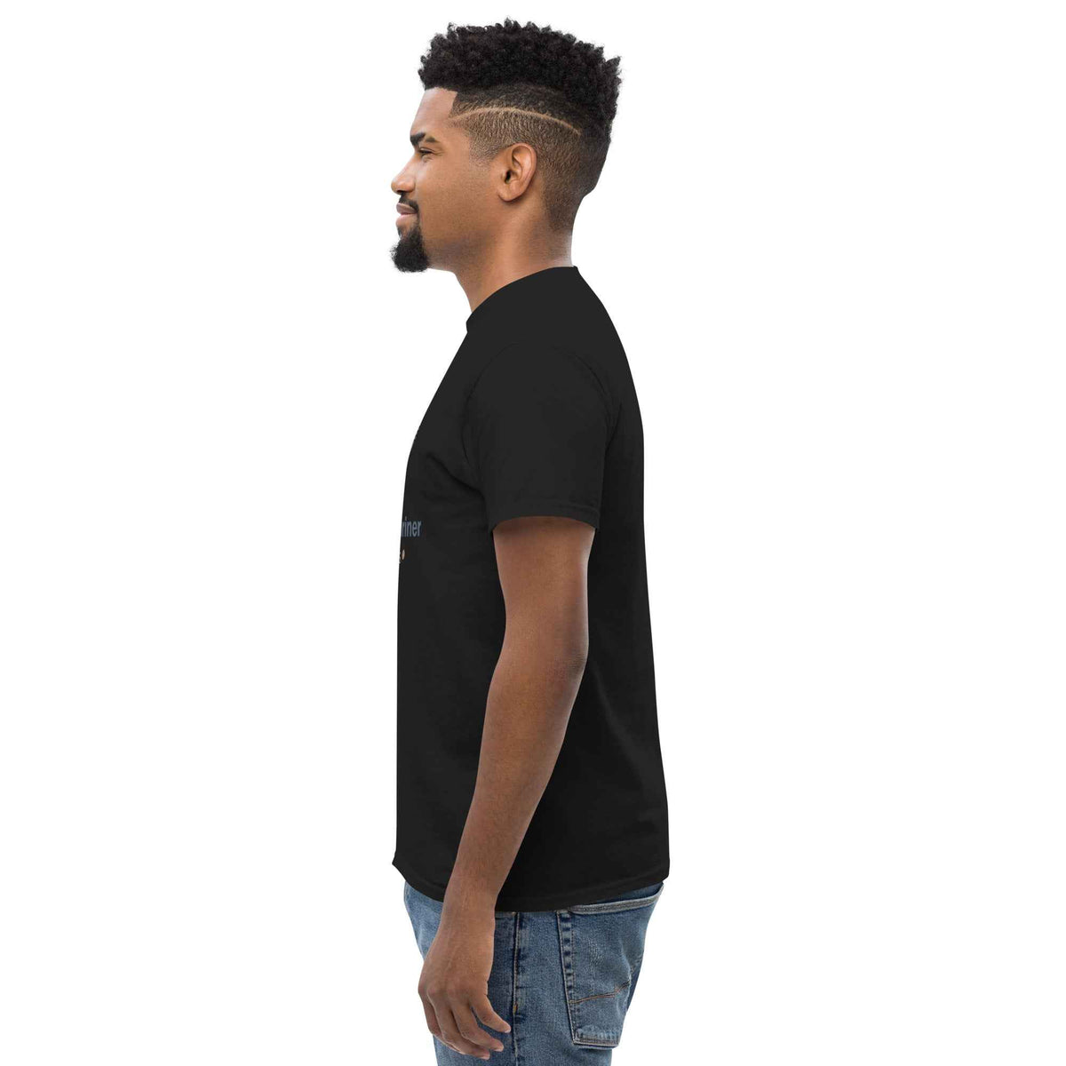 Black unisex classic tee: side profile view on a male model standing and facing left, against a clean studio background shot